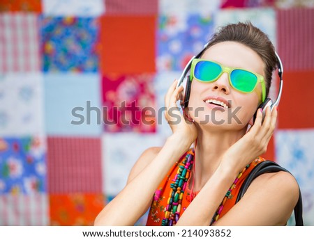 Young woman with headphones listening music .Music fashion girl  against colorful bright background.  focus on mouth, grain added