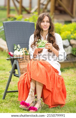 Romantic relaxing girl drinking green chamomile tea outdoors on green natural background