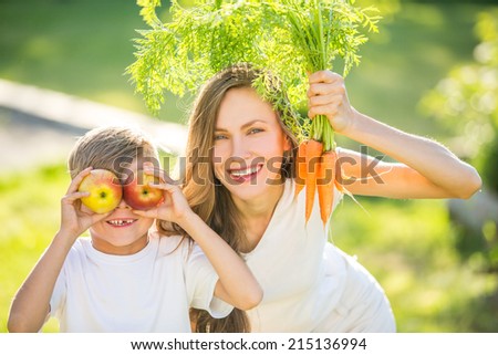 Happy mother and son with vegetables. outdoor shot. focus on mothers face