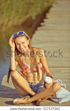 Beach vacation. Hot beautiful woman in bikini happy smiling sitting on bridge