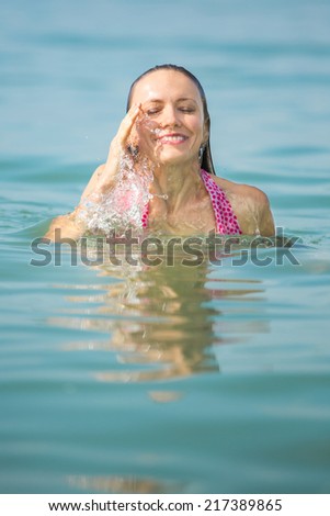 Beautiful young woman swimming in blue sea, under summer daylight. motion