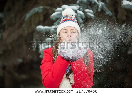 Christmas girl. Winter woman blowing snow on herself. Funny winter woman play with snow