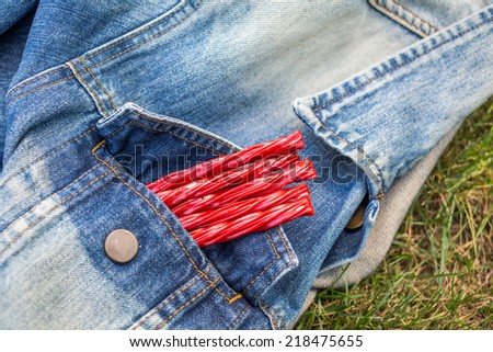 Bright Red Licorice Candy shaped like a twisted rope in a denim jacket