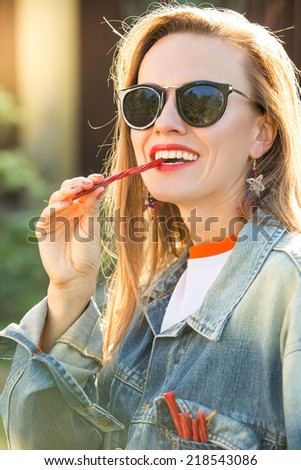 Candy woman eat sweets. Young beautiful girl in sunglasses eating licorice candy over sunshine. soft daylight