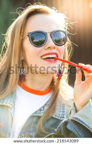 Candy woman eat sweets. Young beautiful girl in sunglasses eating licorice candy over sunshine. soft daylight
