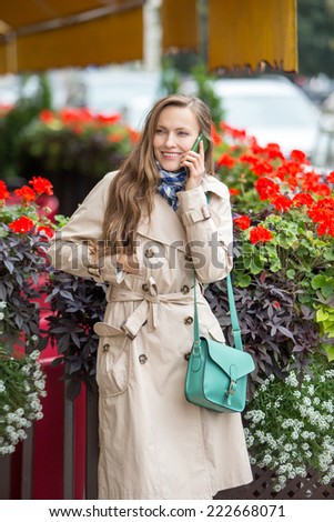 Young woman on smart phone - young business woman using smartphone smiling happy in the street with european cafe in the background