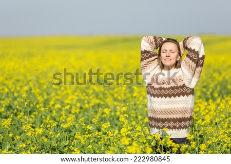 Freedom woman in free happiness bliss on yellow field. Smiling happy female model in knitted sweater enjoying nature during travel holidays vacation outdoors