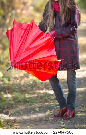 Woman with red umbrella walking in park in fall. focus on umbrella
