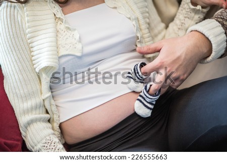 Future parents. Future father holding small socks on belly of pregnant woman. toned image