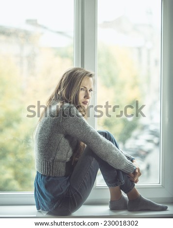 Beautiful young woman sitting by the window. shadows
