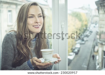 beautiful girl enjoying the freshness of the new day, drinking morning tea of coffee by the window