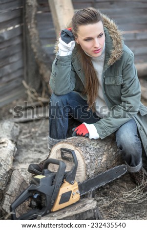 Beautiful female woodworker with chainsaw. focus on woman, daylight
