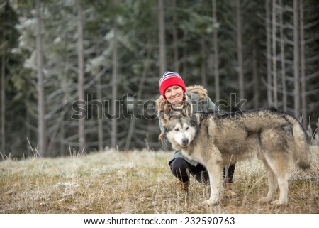 Woman and Alaskan Malamute walk in autumn forest. focus on woman, copy space