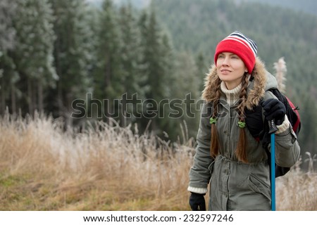 Woman with hiking equipment walking in mountain forest. daylight