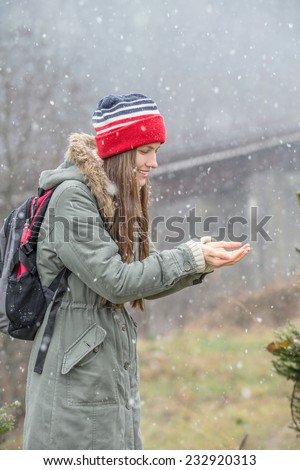 Young traveler enjoy her trip and first snow trying to catch with her hands