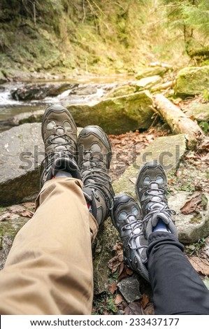 two hikers legs on a hiking path relaxing near mountain waterfall in autumn nature. sunlight