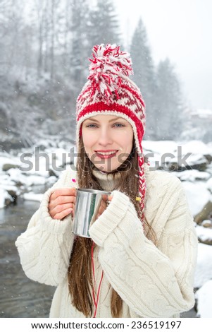 winter portrait woman drinking hot tea over amazing snowy landscape. focus on face