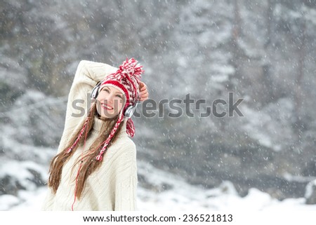 girl listening to music during snowfall, enjoying the beginning of winter and first snow