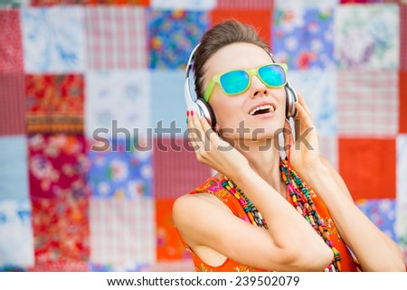 Young beautiful woman in bright outfit enjoying the music over bright background