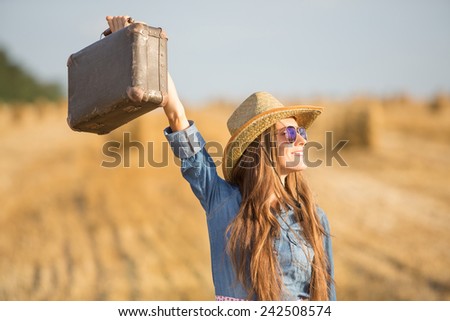 Woman with suitcase over summer field. soft backlight