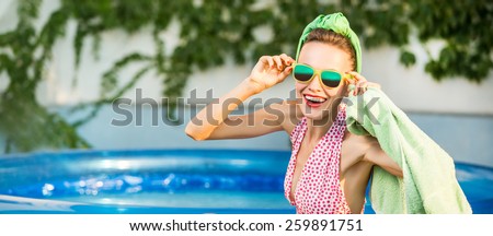 Beautiful young girl in retro look with red lips in retro swimsuit, sunglasses in swimming pool. soft daylight,  copy space