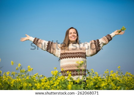 Freedom woman in free happiness bliss on yellow field and blue sky. Smiling happy female model in knitted sweater enjoying nature during travel holidays vacation outdoors