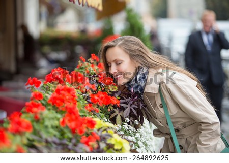 Portrait of beautiful woman walking in the street and smelling flowers. After office relaxation concept