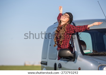 Freedom car travel concept - woman relaxing out of window in a car over blue sky background. Girl relaxing enjoying free holidays road trip. soft daylight
