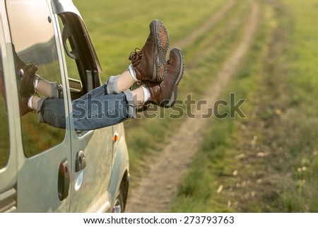 Woman legs against road and grass background. Freedom car travel concept