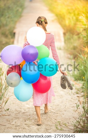 Vintage image of beautiful woman with colorful balloons walking on wooden bridge. grain added, focus on balloons