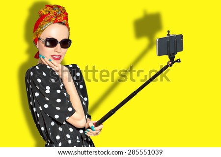 Fashion woman taking selfie over yellow background. focus on woman