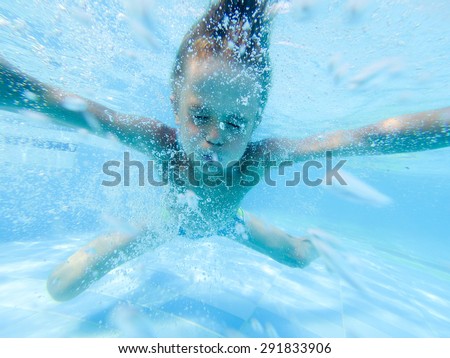 Cute boy swimming underwater in pool, focus on bubbles