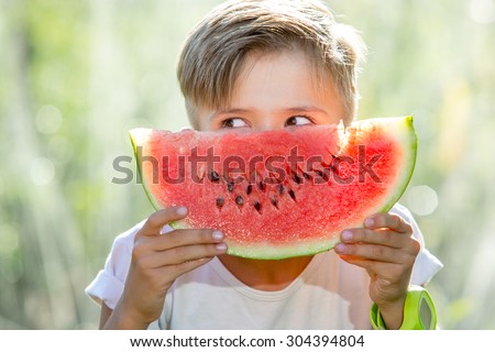 Funny kid eating watermelon outdoors in summer park, focus on eyes. Child, baby, healthy food