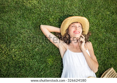 Happy young woman lying on green grass and dreaming. copy space, view from above, soft
