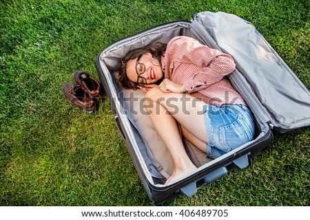 Funny traveler woman sitting in a huge suitcase and plan her trip