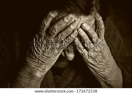 Toned portrait of an old woman with hands on face