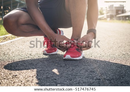 Running shoes. Barefoot running shoes closeup. Male athlete tying laces for jogging on road in minimalistic barefoot running shoes. Runner getting ready for training. Sport lifestyle.