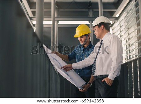 Engineers in mechanical factory reading instructions.Engineer and businessman meeting, team discussion with construction on site work.