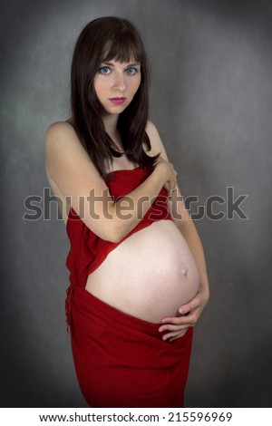Young brunette beautiful woman pregnancy nude belly in red