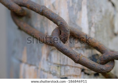 Rusted link of the chain on wood texture background