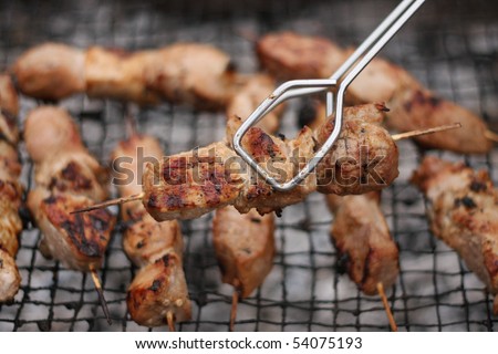 Roasted meat on wood sticks prepared for eating. Barbecue. Shallow depth of field.