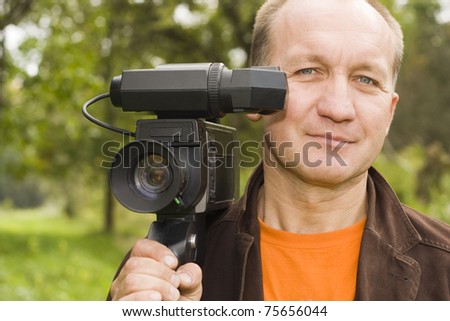 a grown man posing with a video camera on his shoulder.