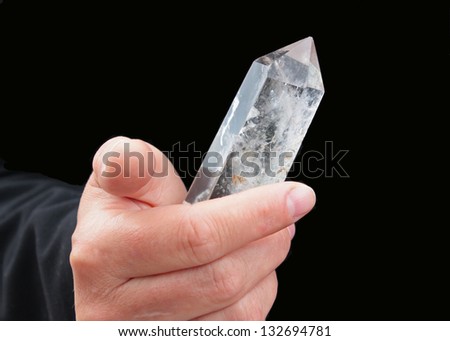 The rock crystal crystal is shone in a hand. The dark background is chosen.