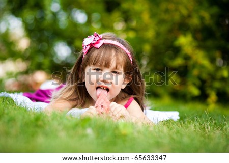 cute little girl eating water-melon on the grass in summertime