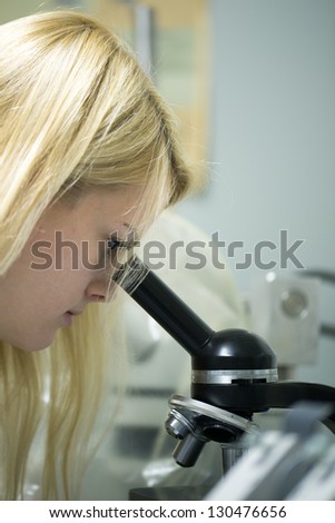 young blond female scientist works with microscope