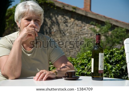 elderly woman drinks wine outside