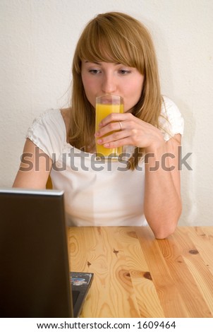 young  woman working with laptop and drinking orange juice