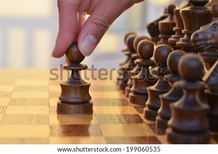 A table with chess standing in two rows and a hand moving a pawn