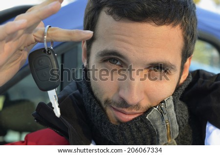 A handsome black-haired man  dressed in winter clothes holding a car key on his finger