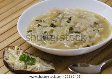 A plate of french onion soup with a slice of bread with melted cheese
